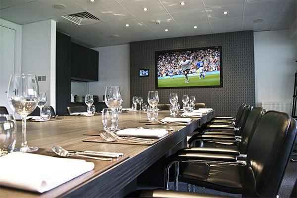 The Cinos Suite, laid out for match day dining, showing the 80” NEC screen and AMX touch panel ready for ordering directly from the bar. 